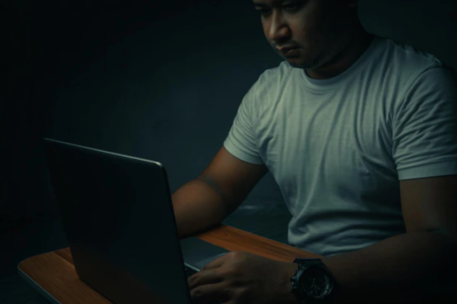 Persona frente al portátil en la oscuridad, metáfora visual de adicción al sexo y uso oculto de internet.