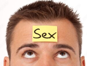 Hombre mirando hacia una nota con la palabra “sex” en su frente, metáfora de la compulsión sexual.