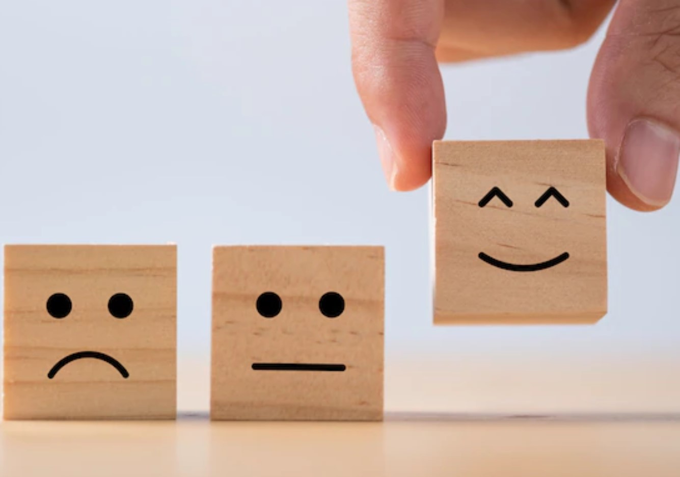 Gestión emocional representada con cubos de madera con diferentes expresiones faciales.