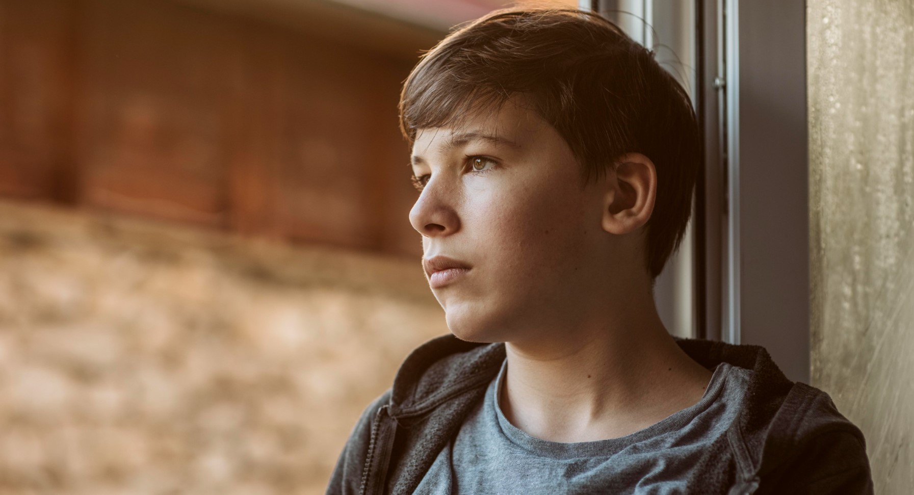 Adolescente pensativo mirando por la ventana, reflejando preocupaciones emocionales propias de esta etapa como la depresión.