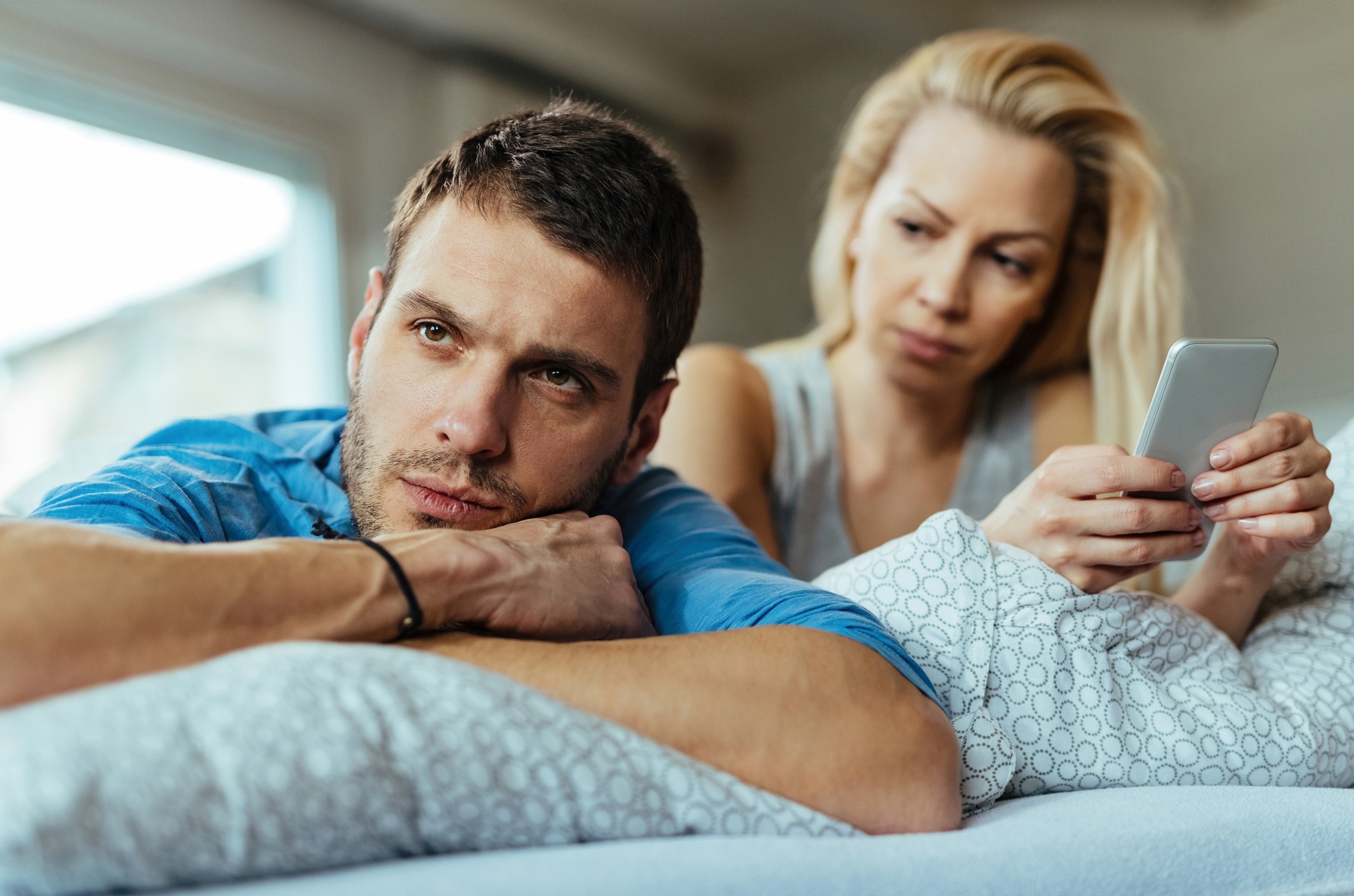 Fidelidad emocional en crisis: pareja en la cama con evidente malestar.