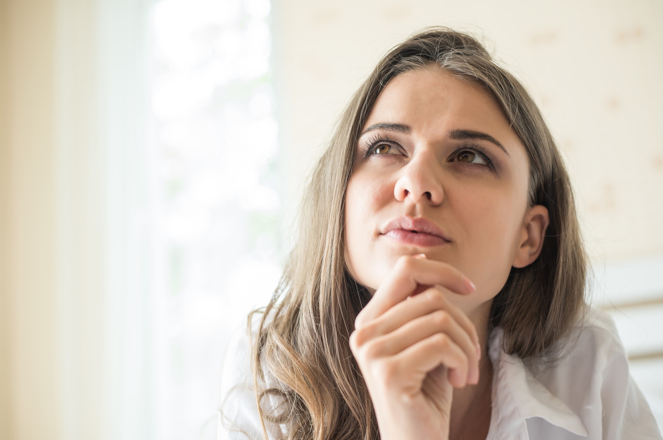 Mujer pensativa reflexionando sobre expectativas poco realistas.