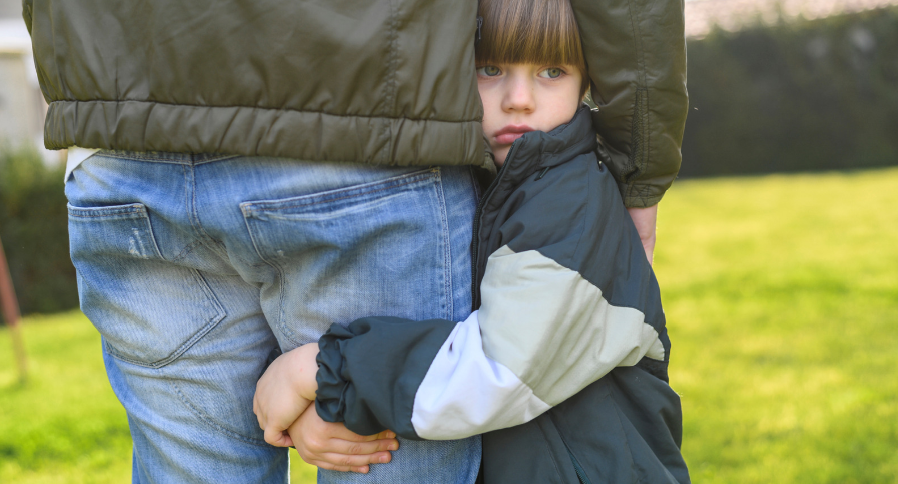 Mutismo selectivo representado por un niño aferrado a la pierna de su padre