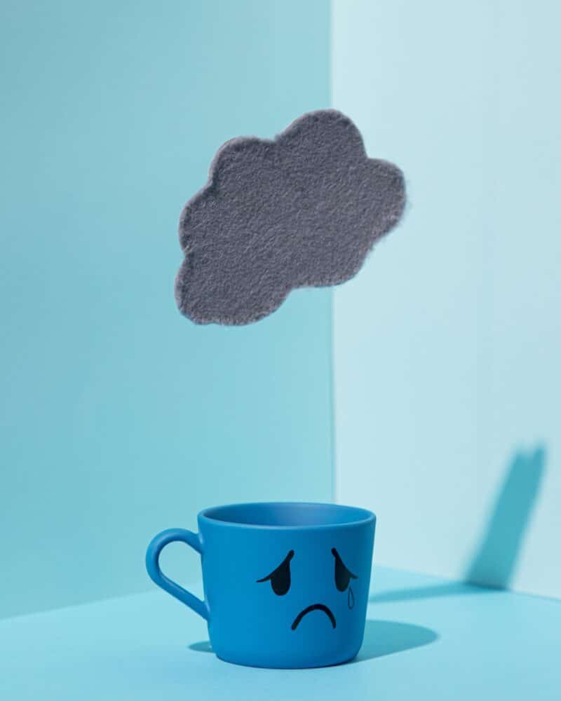 Cuesta emocional representada por una taza triste bajo una nube negra